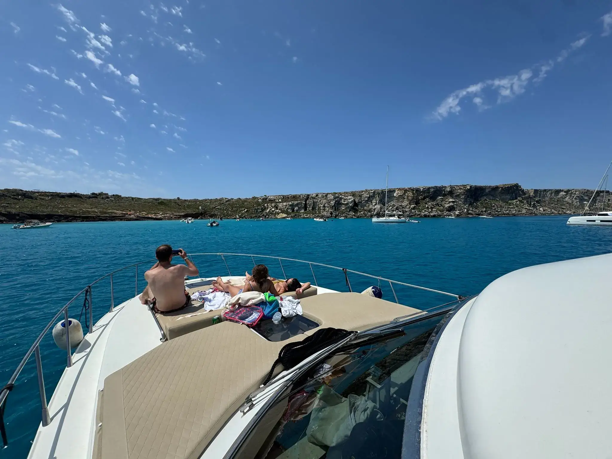Friends on the bow of the boat in a cove in the Egadi Islands