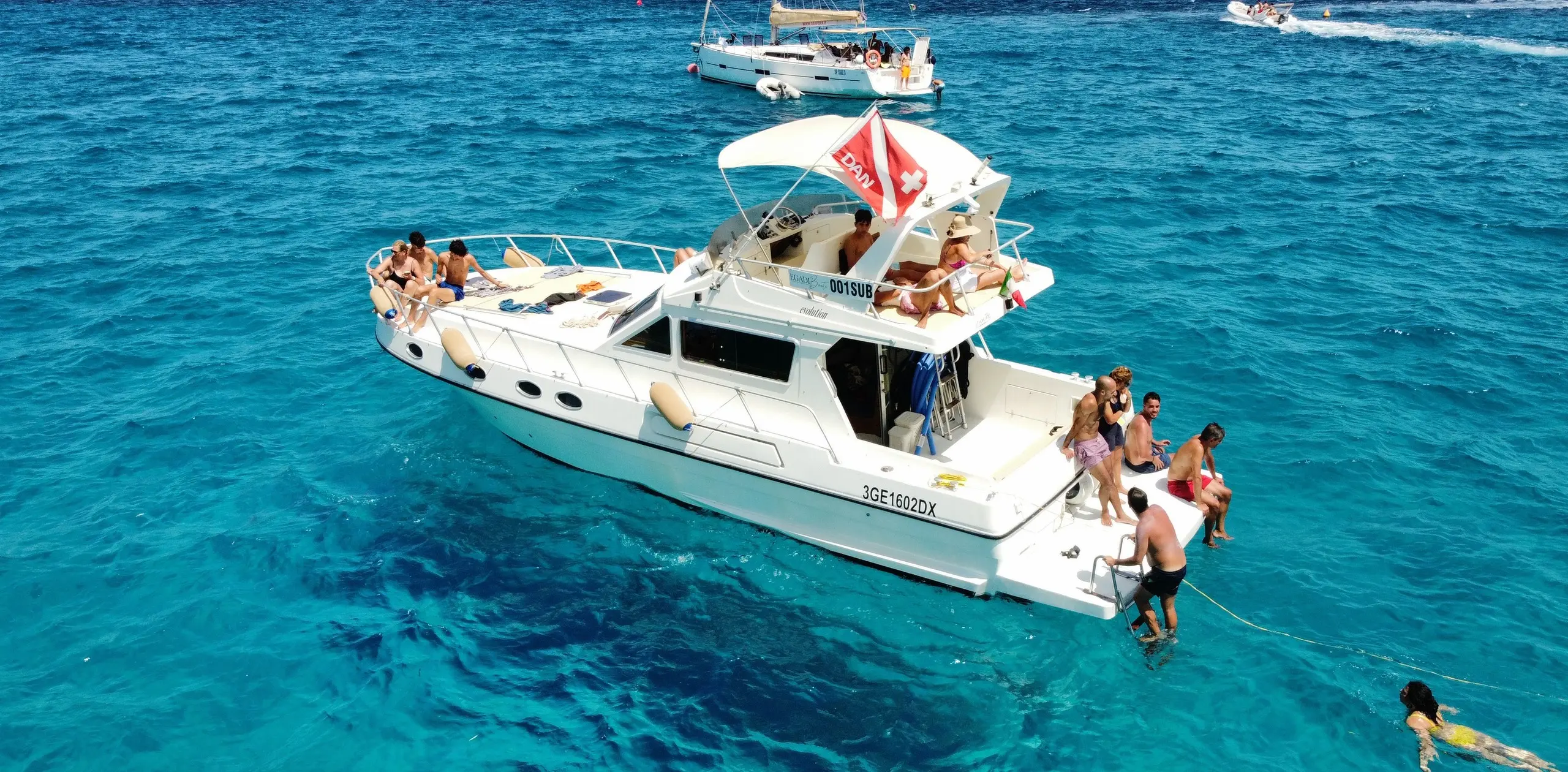 Guests stepping into the water from the boat's stern, turquoise sea