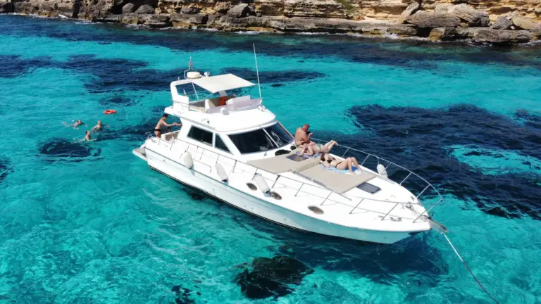 Helena all'ancora nell'acqua turchese sotto la costa di tufo di Favignana, ospiti in acqua